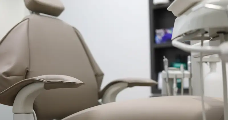 Close-up of dental chair and equipment in a clinical setting, emphasizing healthcare technology.